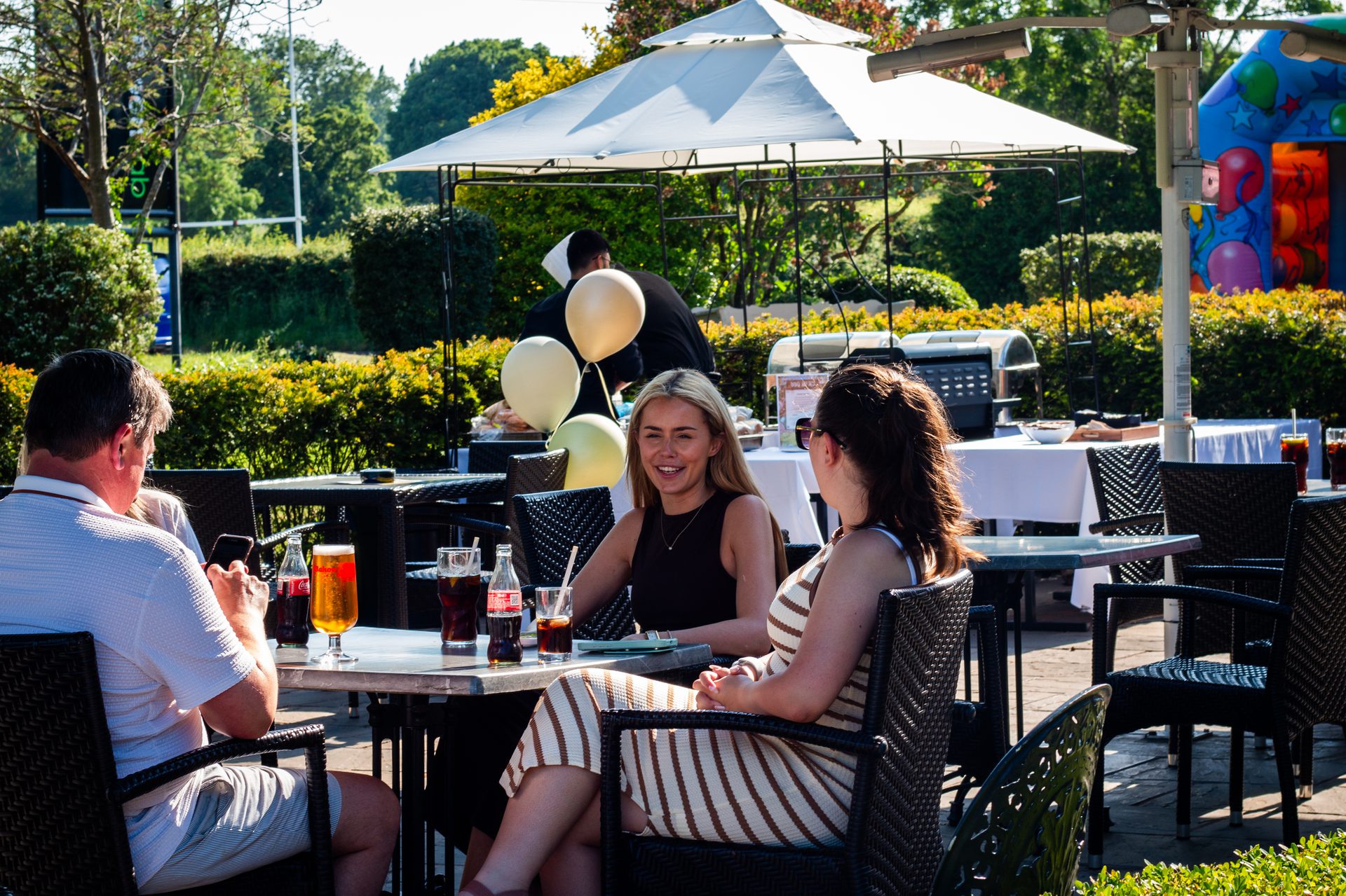 Guests enjoying drinks on the sunny outdoor terrace at The Twisted Boot Bar